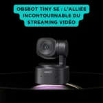 OBSBOT Tiny SE : La Webcam AI PTZ Full HD à Suivi Automatique pour un Streaming Sans Faute Webcam OBSBOT Tiny SE noire à tête motorisée intelligente, posée sur socle et éclairée, présentée sur fond noir avec encart turquoise soulignant son rôle pour le streaming vidéo.